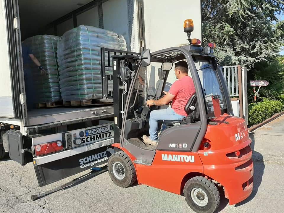 Un uomo guida un carrello elevatore rosso accanto a un camion.
