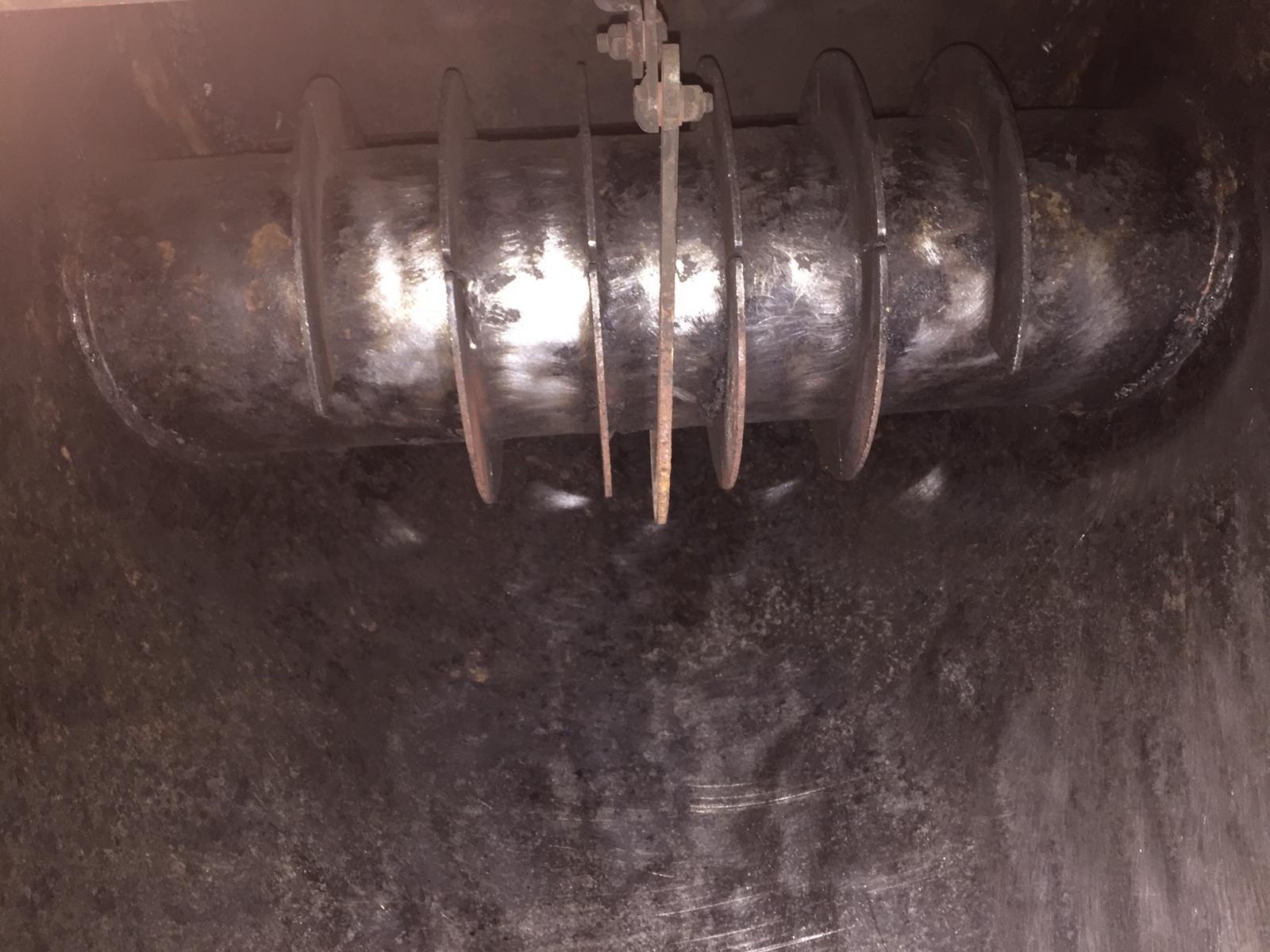 Interno di un apparecchio di metallo scuro con una vite rotante e aste metalliche pendenti.