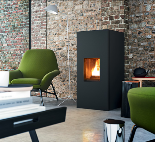 Soggiorno moderno con stufa nera, sedia verde e parete in mattoni.