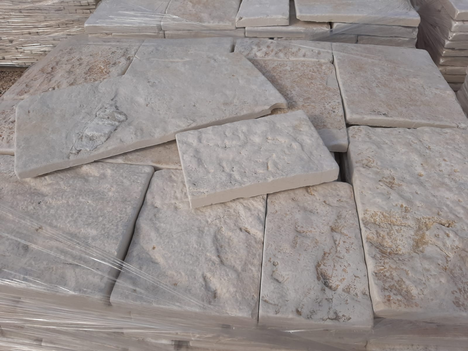 Pila di lastre di pietra rettangolari di colore chiaro, alcune con superfici strutturate.