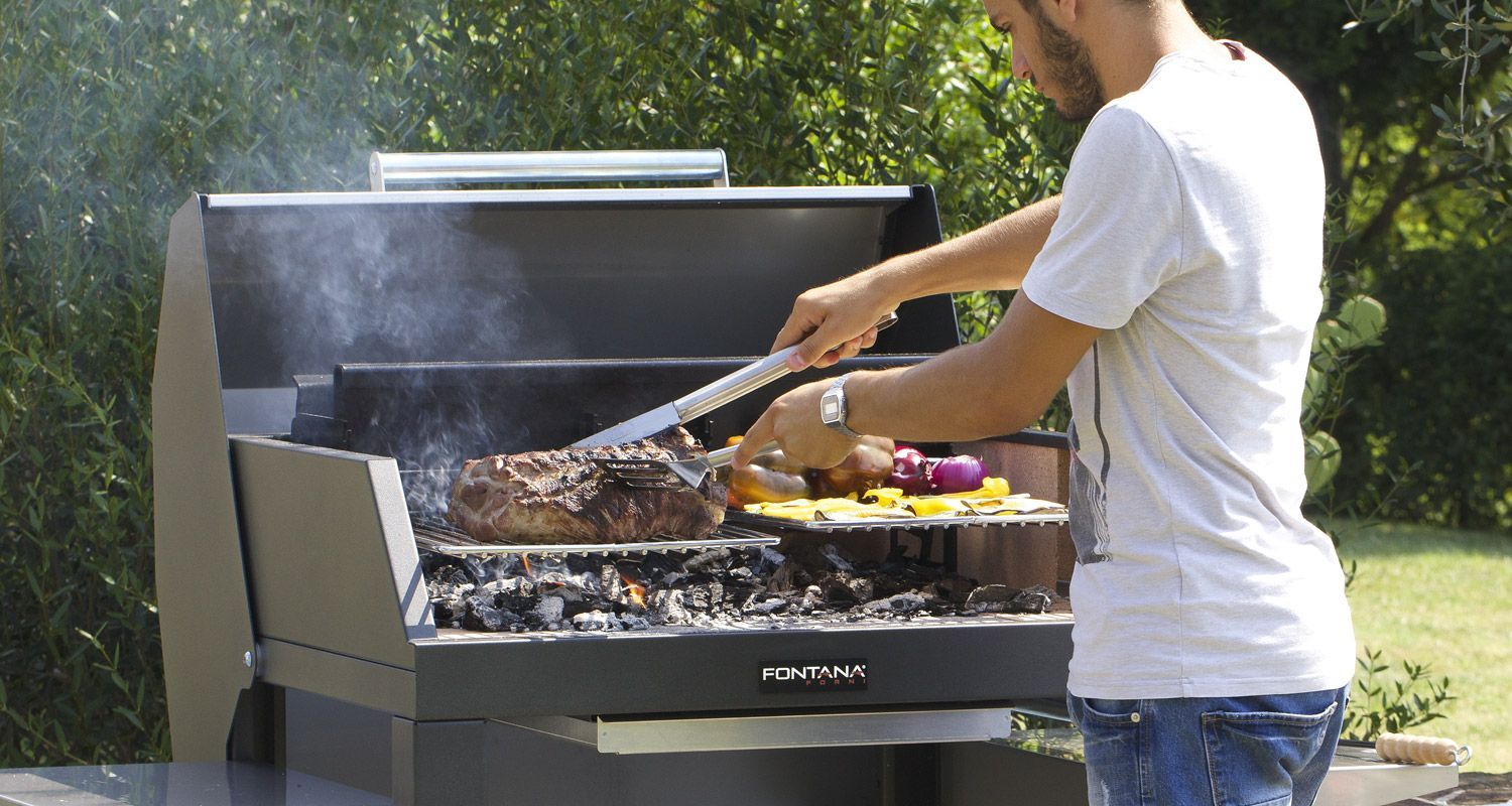 Uomo che griglia bistecca e verdure su una griglia a carbone all'aperto.