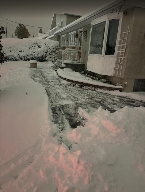 Snow-covered house with cleared walkway. Pathway through the snow to front door. Winter scene.