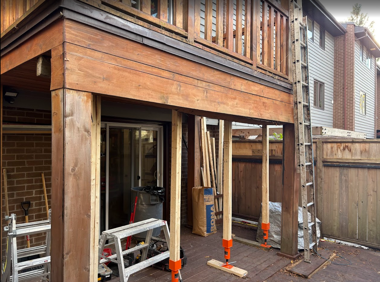 Deck renovation: Wooden deck supported by temporary posts. Ladder leans against the deck's side.