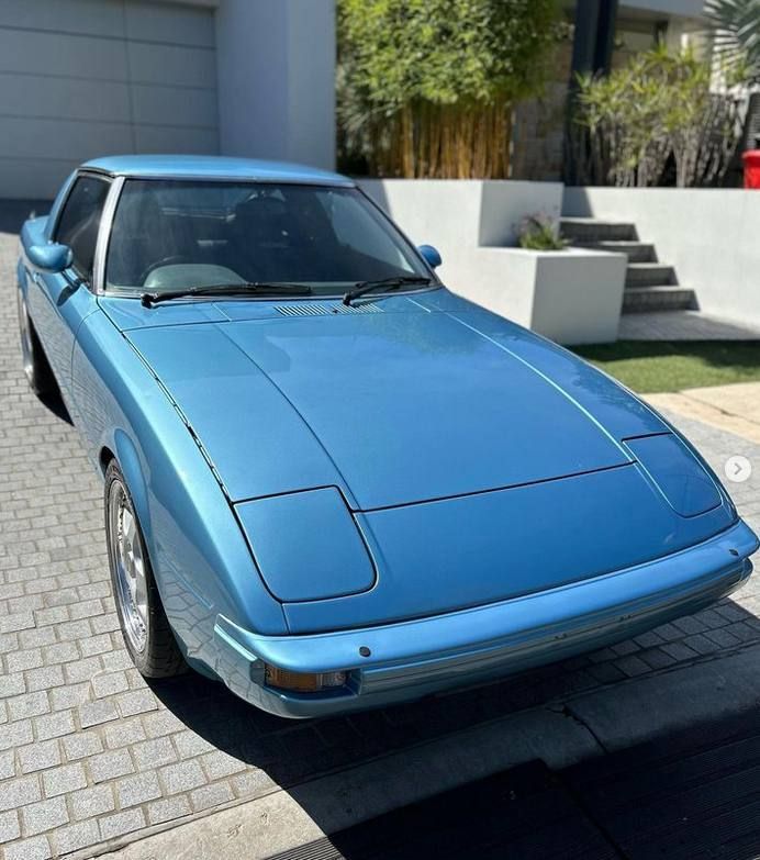 a blue car is parked in front of a garage after applying a ceramic coating
