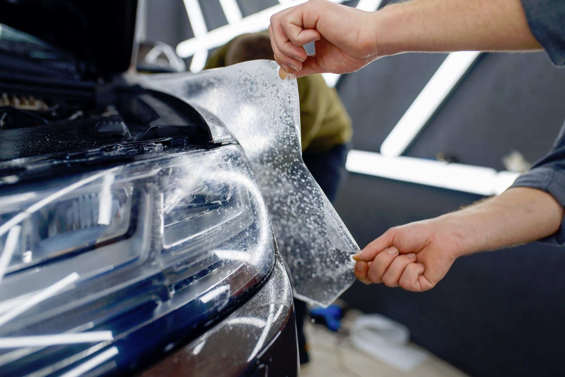 a person is applying a clear film to the headlight of a car