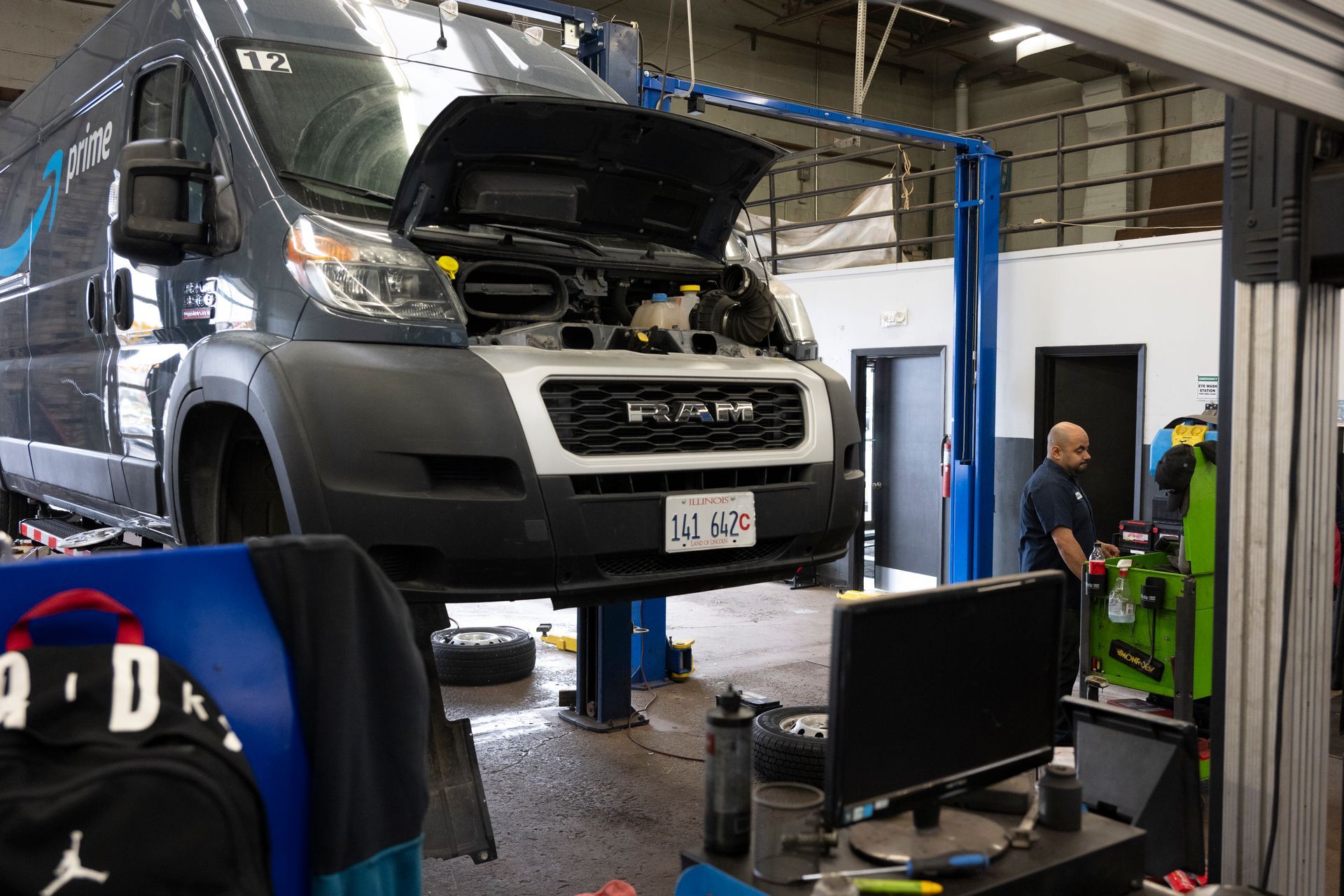A van is being repaired in a garage with the hood up. | Meineke Car Care Center
