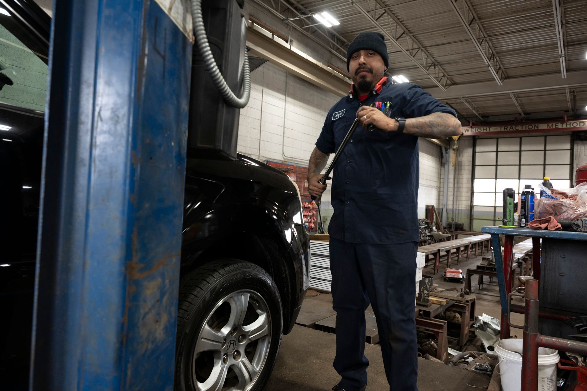 A man is standing next to a black car in a garage. | Meineke Car Care Center