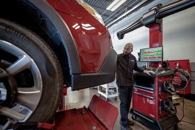 A man is working on a car in a garage. | Meineke Car Care Center