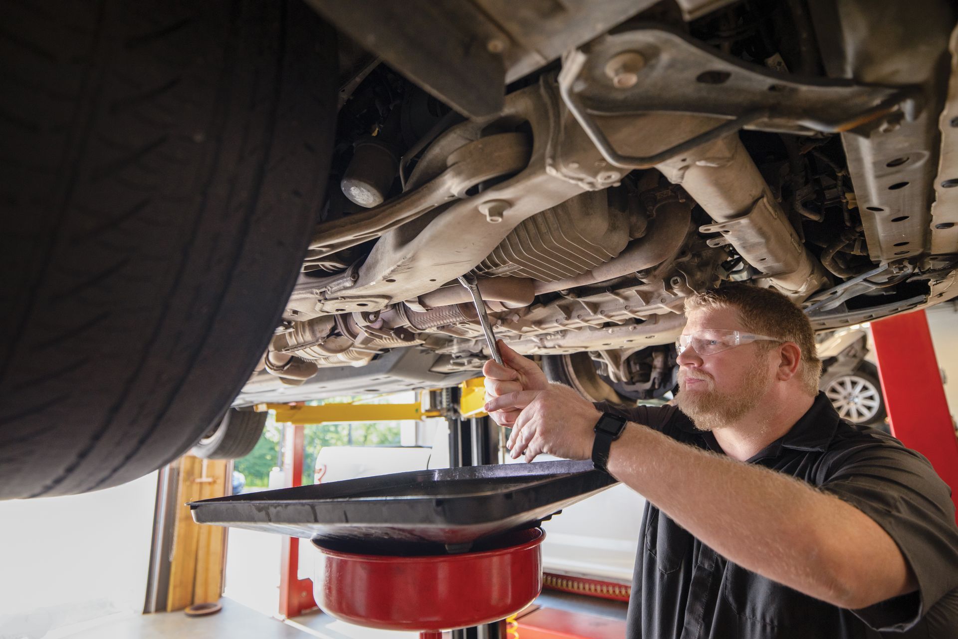 A man is working under a car in a garage. | Meineke Car Care Center