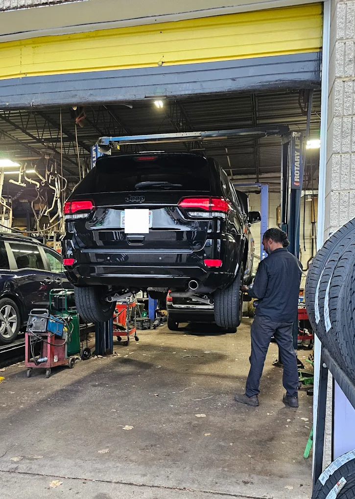 A black suv is parked in a garage with a man standing next to it. | Meineke Car Care Center