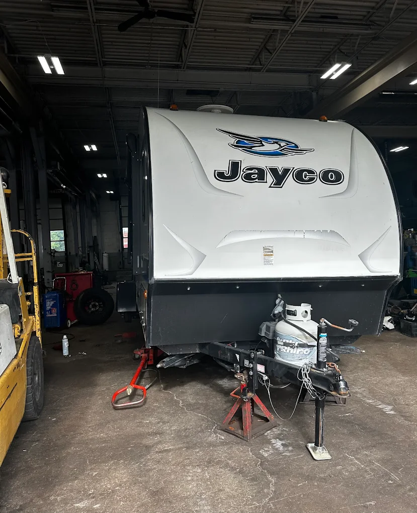 A white and black jayco trailer is parked in a garage. | Meineke Car Care Center