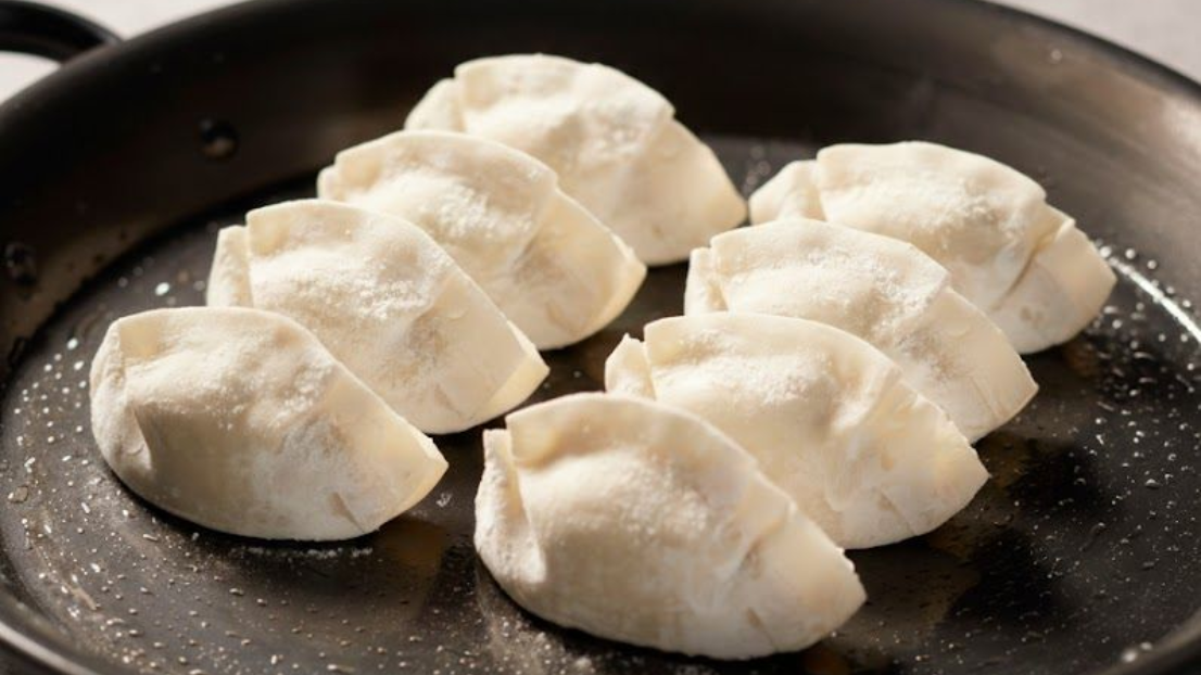 銀鍋中熱氣騰騰的肉末和香草混合物，用白色鍋鏟攪拌。