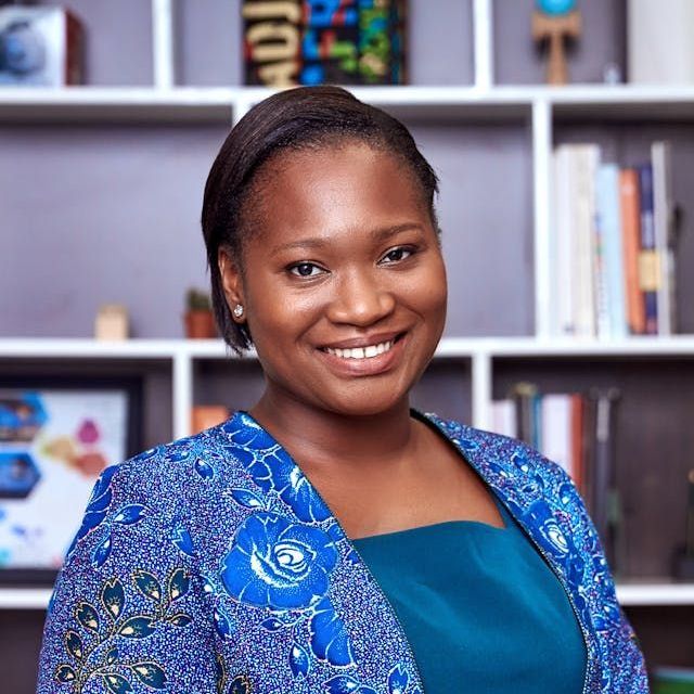 A man in a blue shirt is laughing with his mouth open.