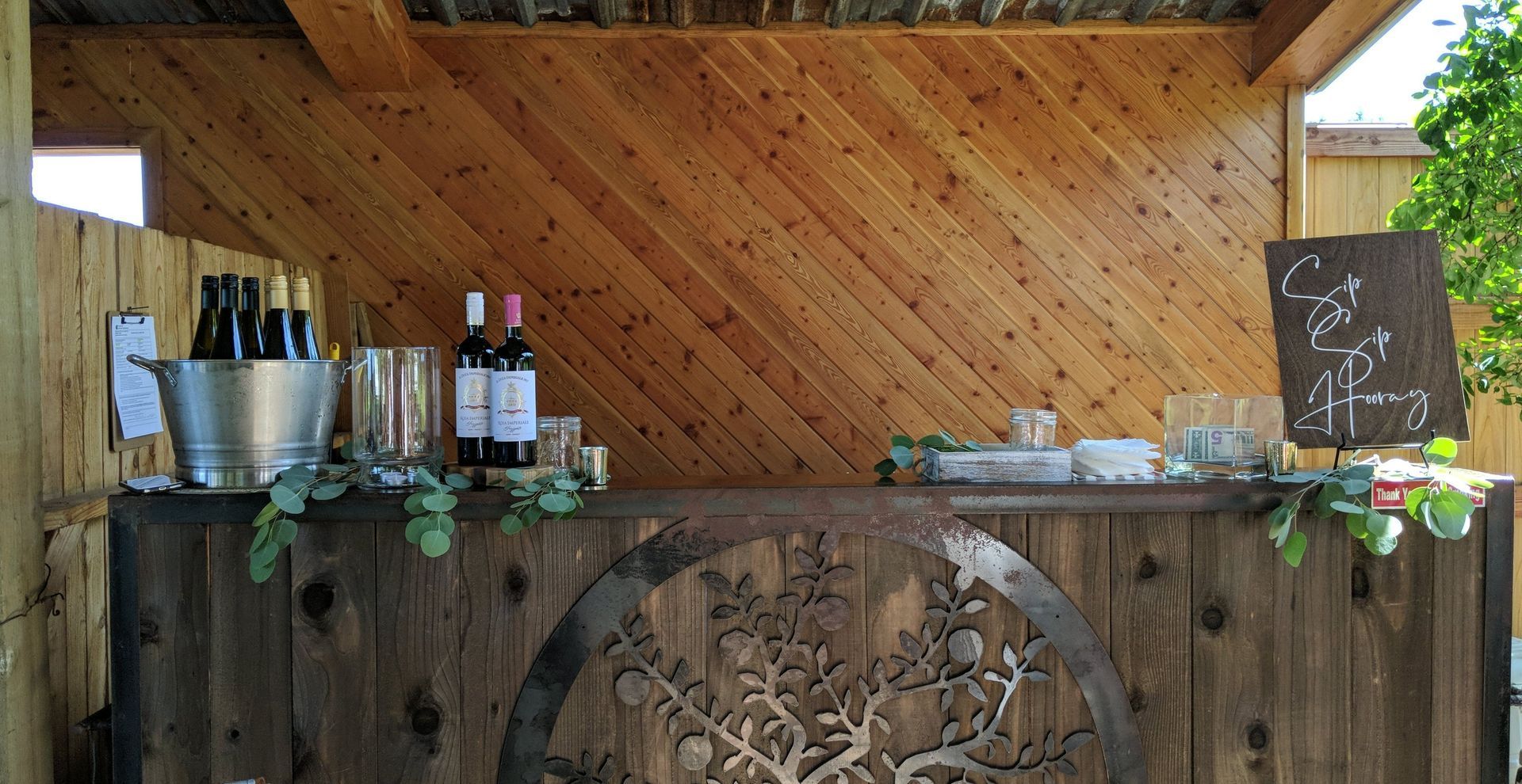 A wooden bar with bottles of wine and glasses on it.