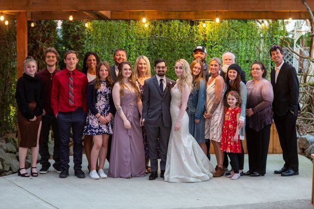 A bride and groom are posing for a picture with their family.