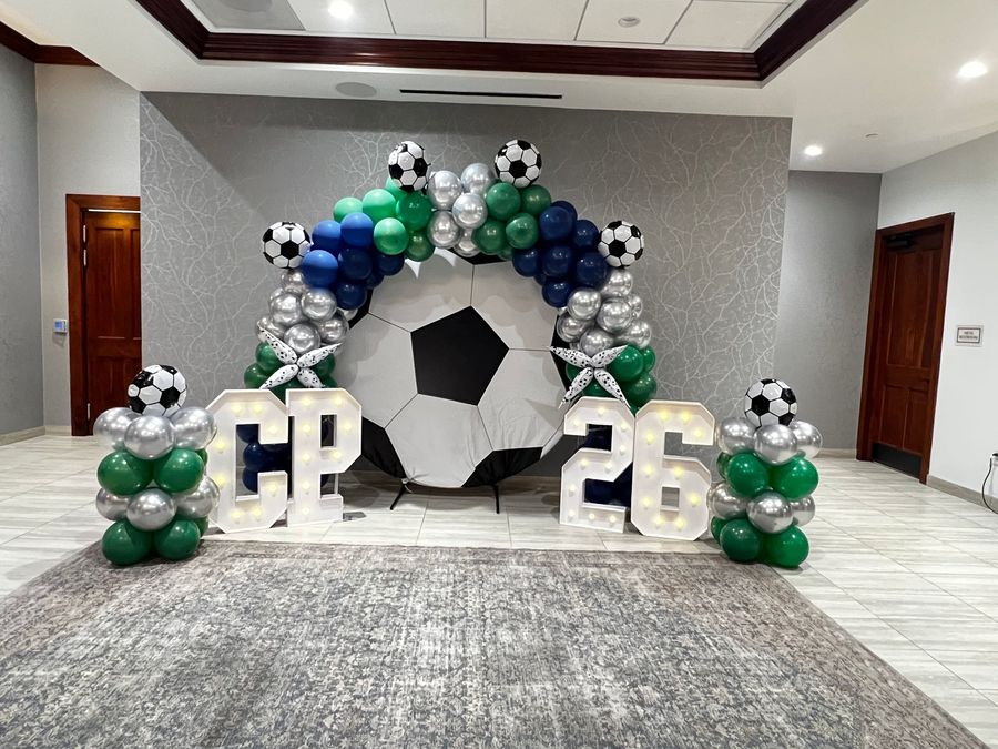 Soccer-themed balloon arch with large “CP 26” letters in a lobby area