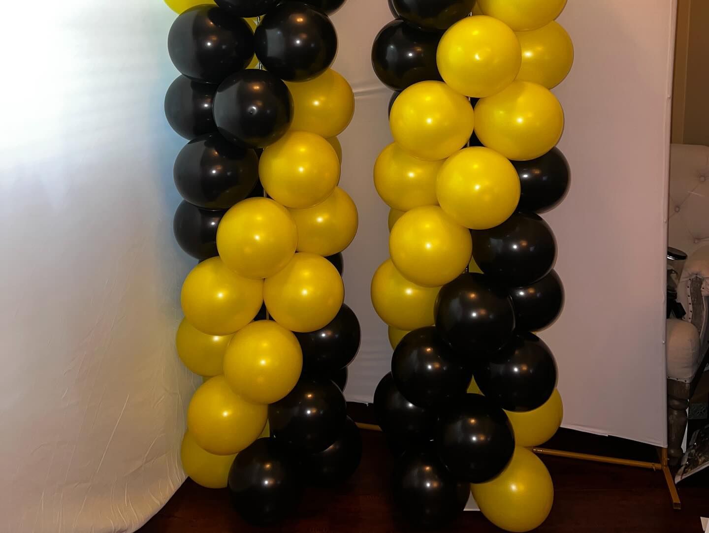 Black and yellow balloon columns forming an arch at an event entrance
