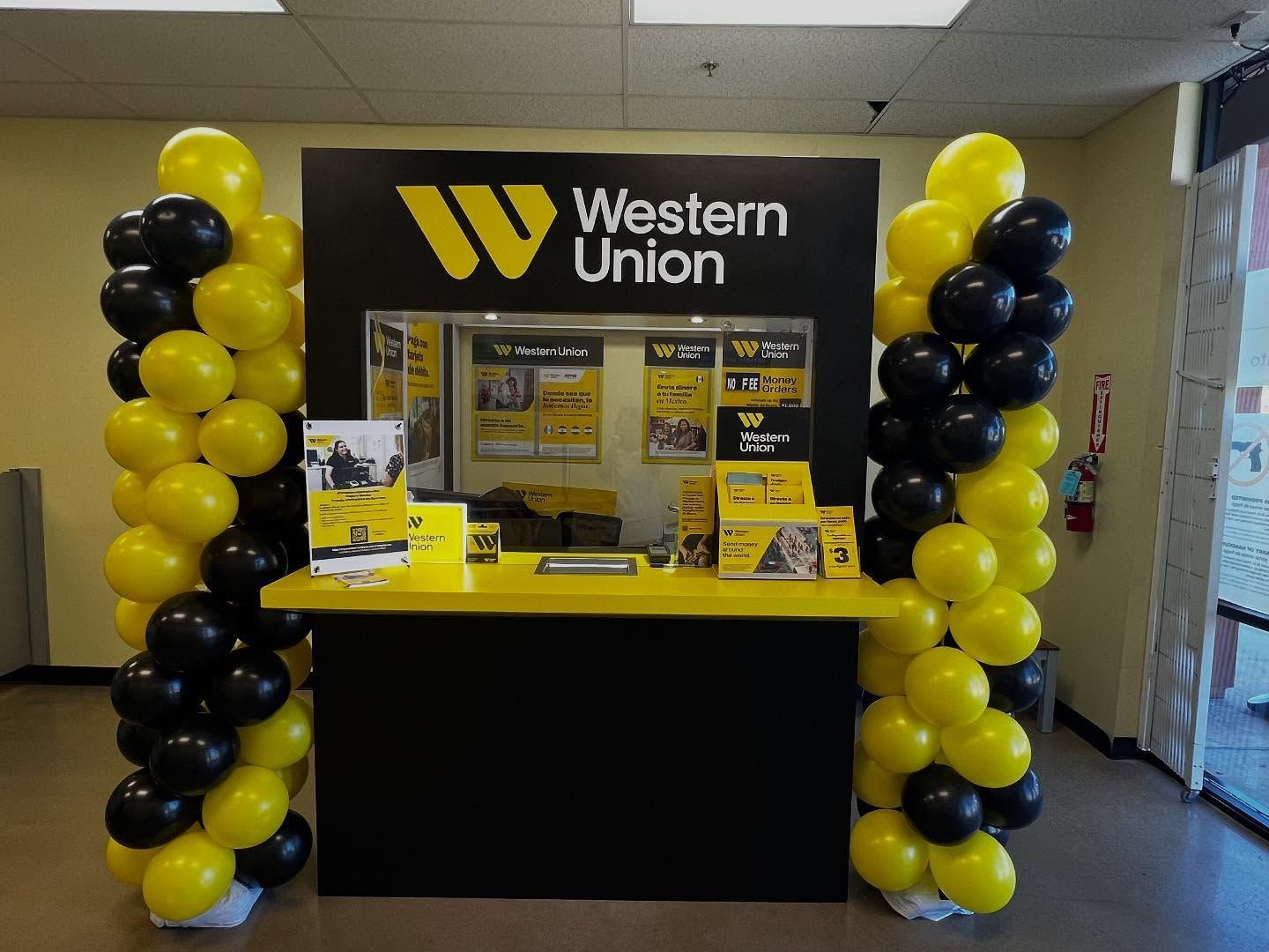 Western Union kiosk with black and yellow balloon decorations in a hallway