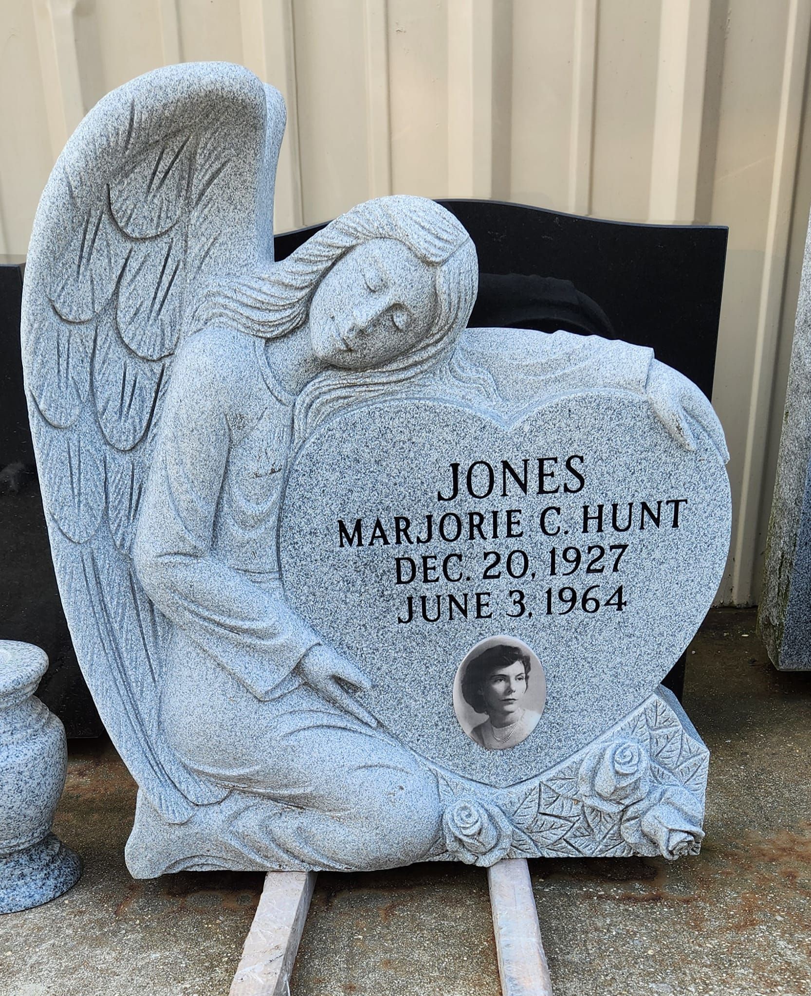 Gravestone shaped like an angel, with text and a photo, grey granite.