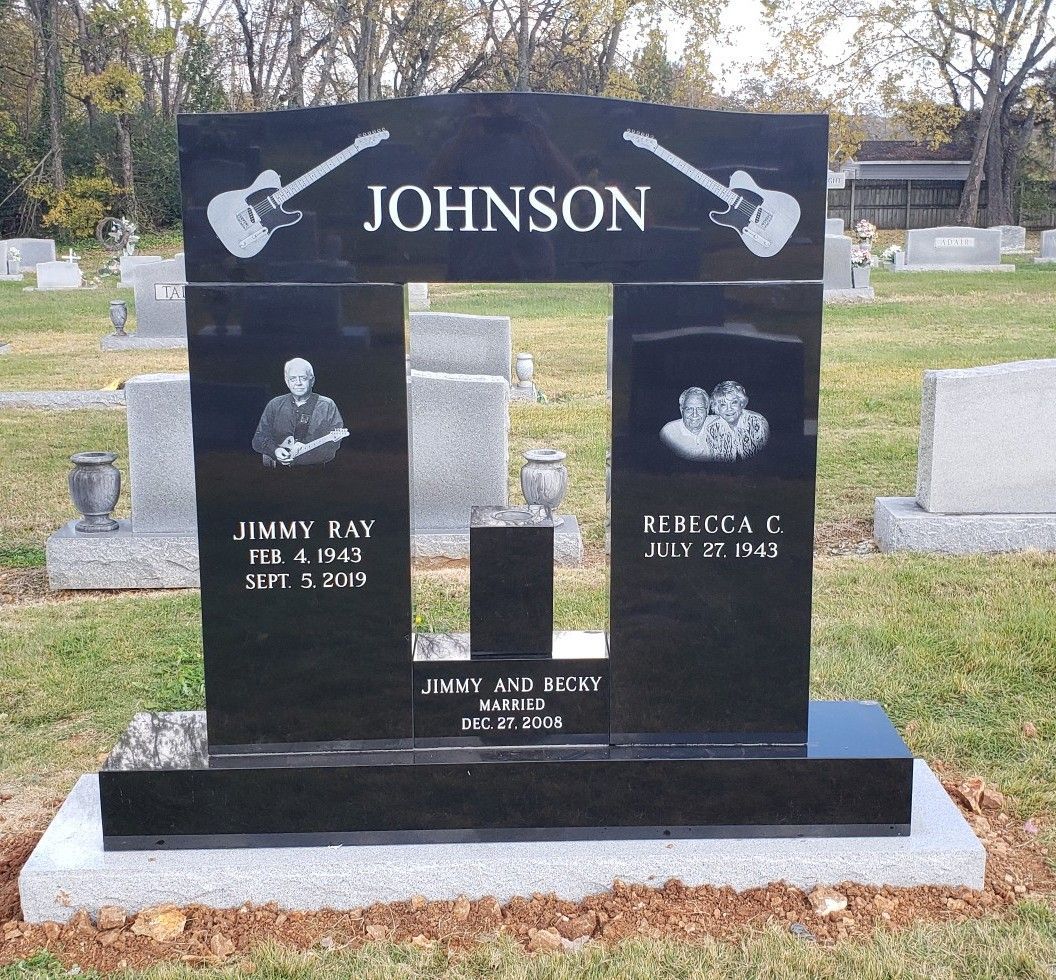 Black granite headstone with guitars, names, and photos in a cemetery.