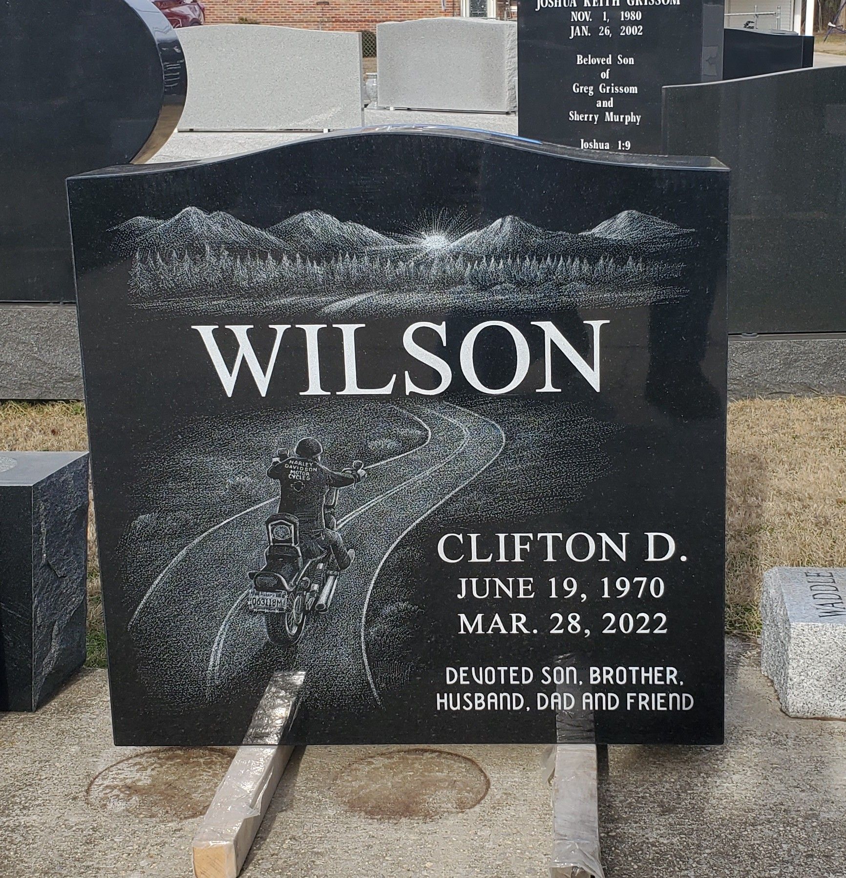 Black headstone with engraved text: