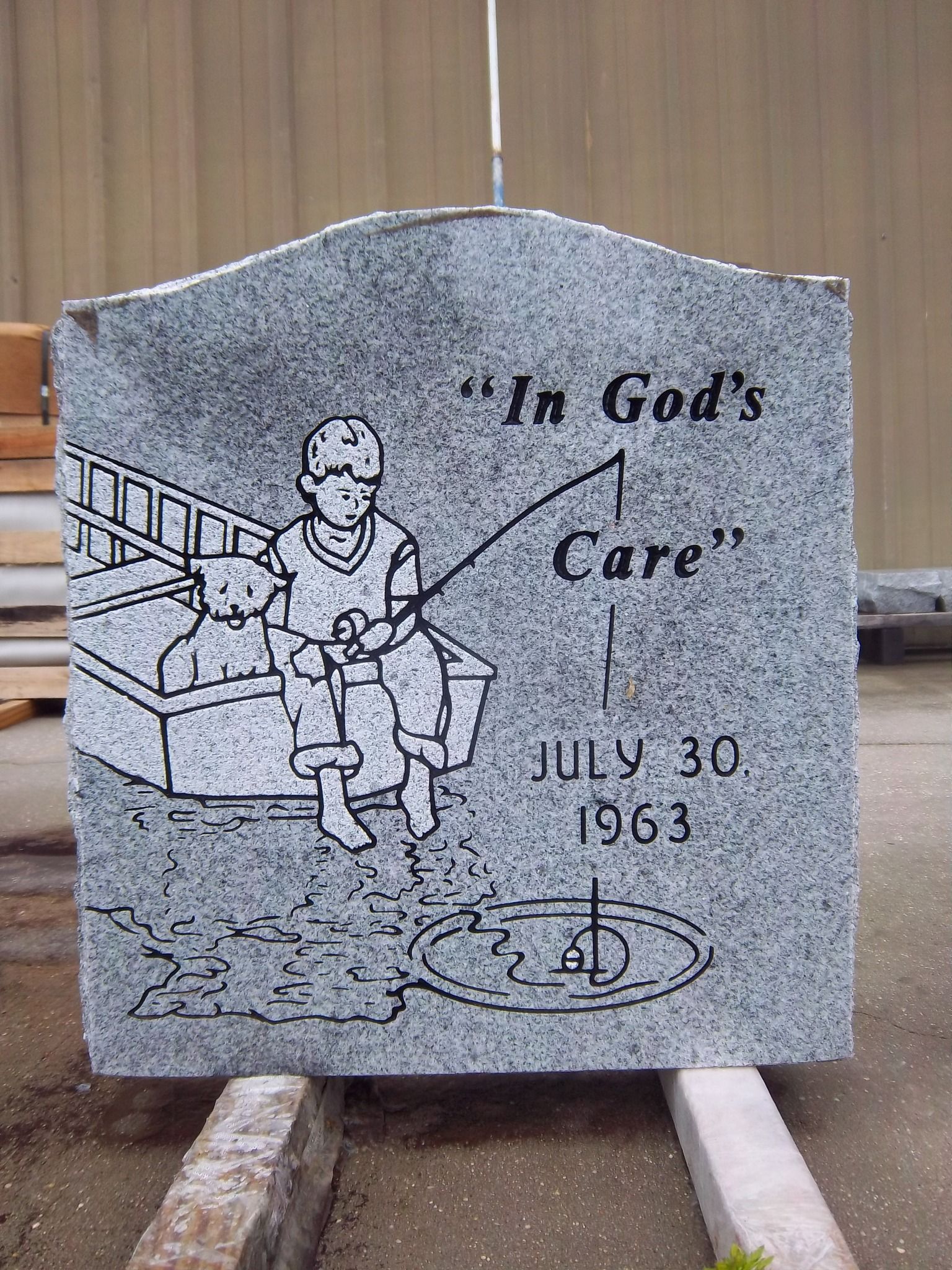 Gravestone with etched image of a child fishing with a dog; inscription