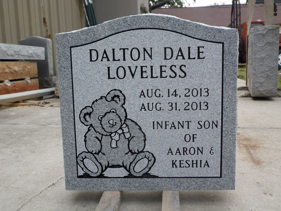 Gray tombstone with teddy bear engraving, inscribed with