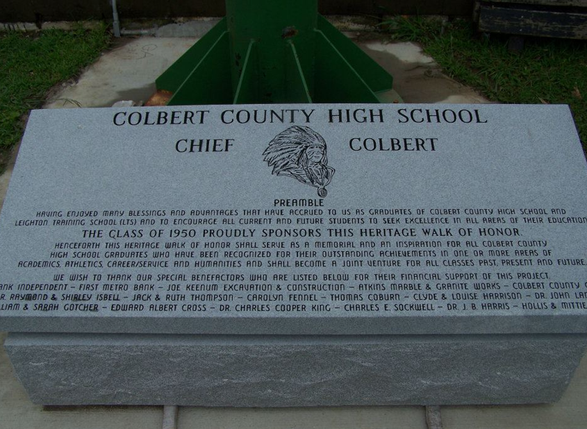 Black granite headstone with name, dates, and etched scene of barn and deer. Two black vases flank it.