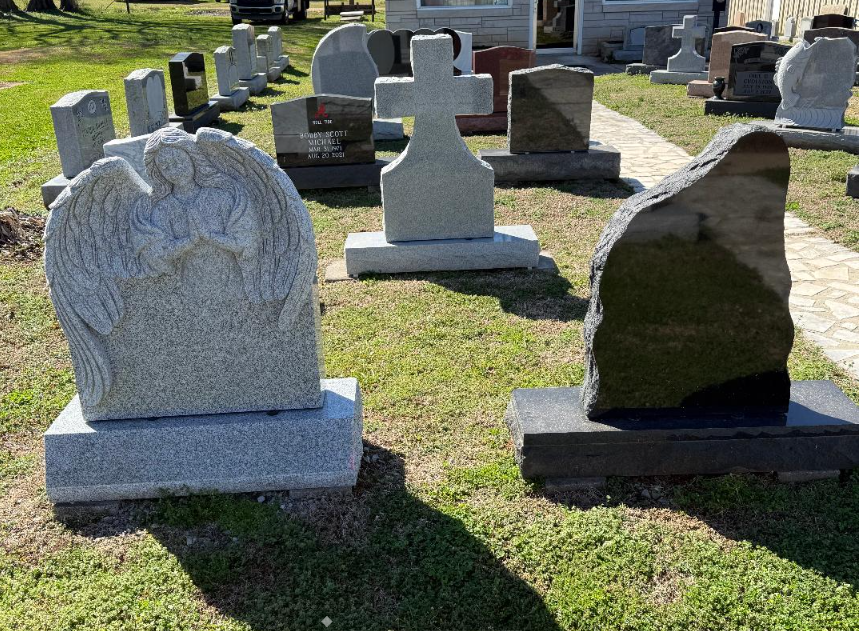 Semi-truck parked next to a cemetery, loaded with construction materials. Gray headstones in foreground.
