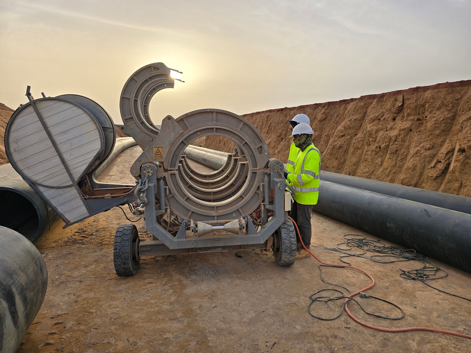 Obrero de la construcción fusionando tuberías con equipo especializado al aire libre.