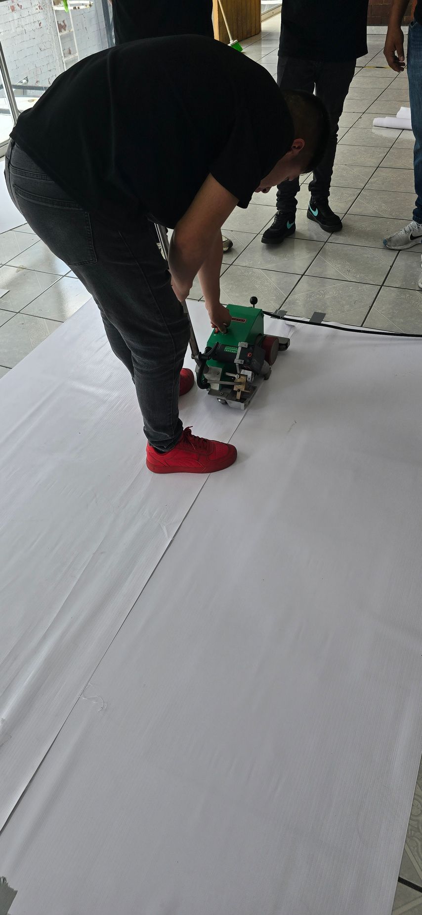 Trabajadores con overoles de color naranja y cascos cortando madera al aire libre.