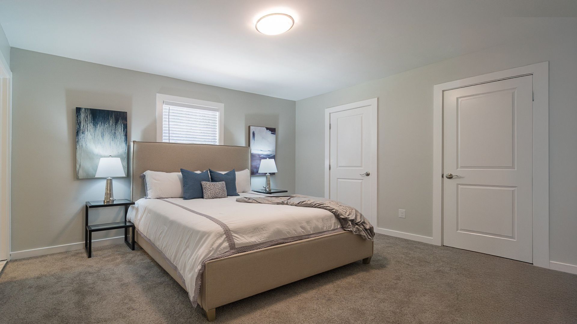 Modern bedroom with beige bed, gray walls, two windows, and closed white closet doors