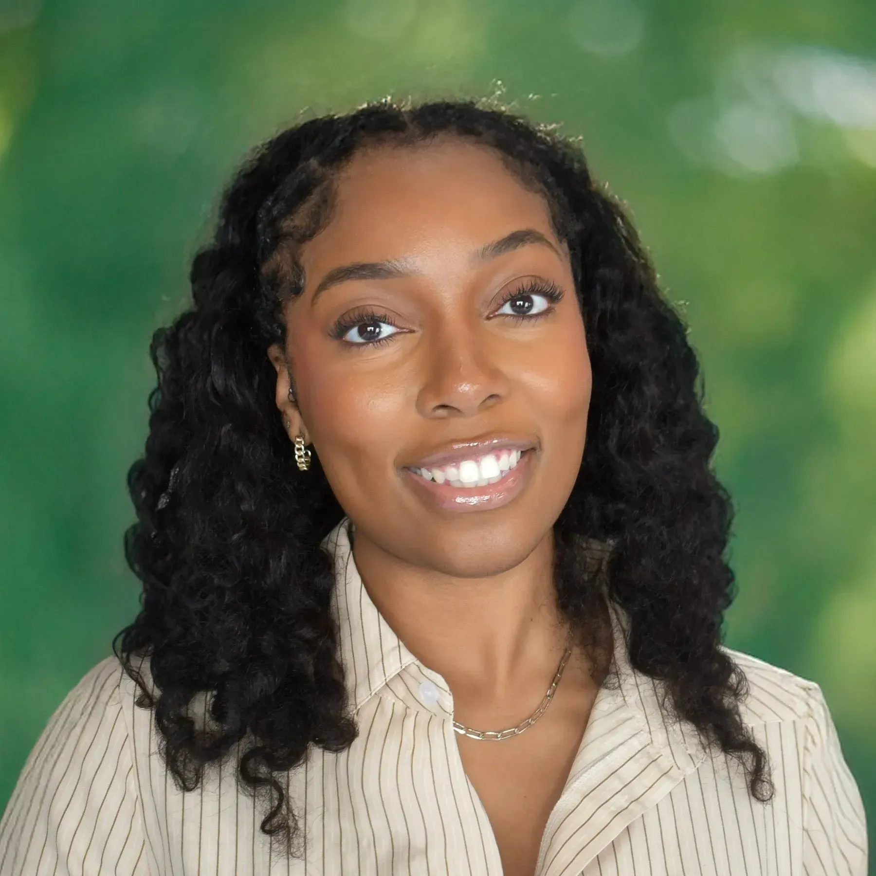 Portrait of a smiling woman with curly hair against a blurred green background