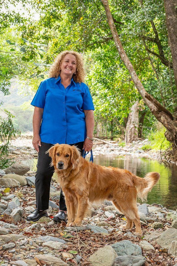 Woman in blue shirt stands by stream with golden retriever.— Canine Training School in Trinity Park, QLD