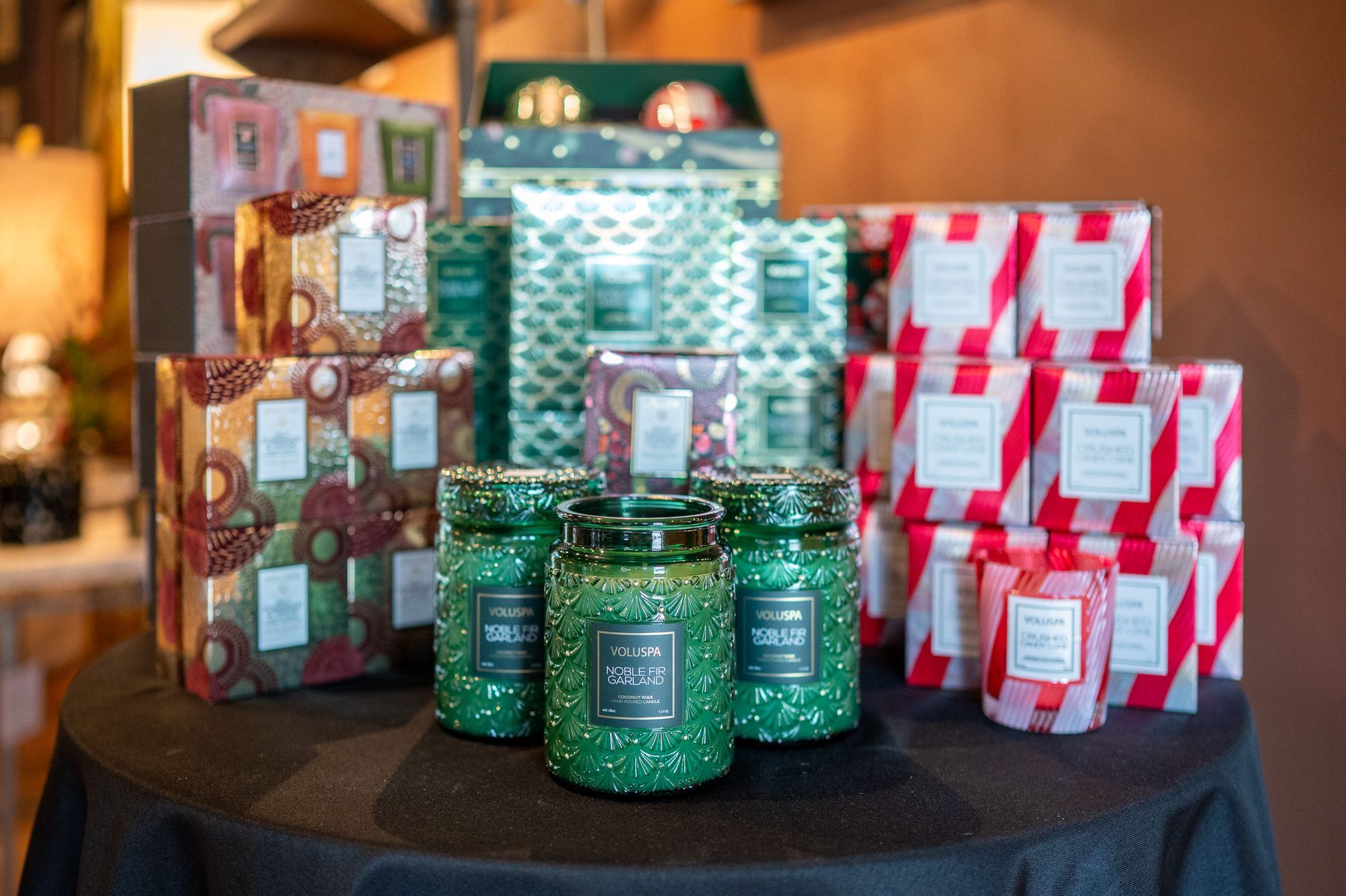 Candles and gift sets in various sizes and festive packaging on a black surface.