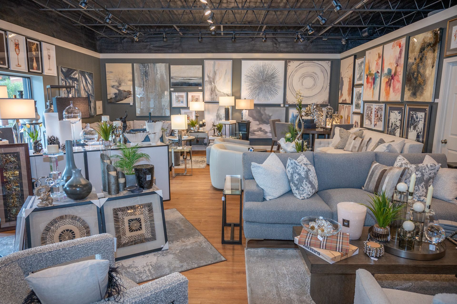Interior of a furniture store with gray sofas, artwork, lamps, and decorative items.