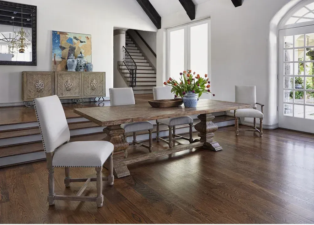 Elegant dining room with wooden table, chairs, and credenza; hardwood floor, white walls, and French doors.
