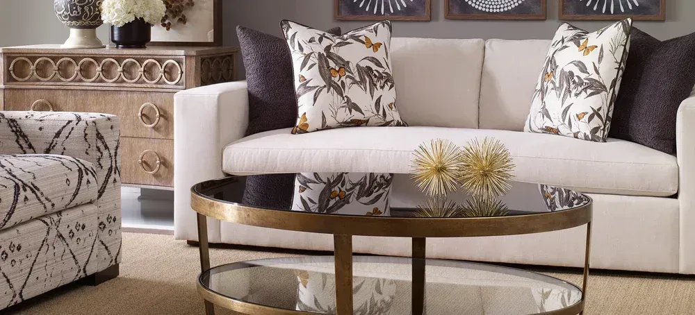 Living room with beige sofa, patterned pillows, round coffee table, and patterned armchair.