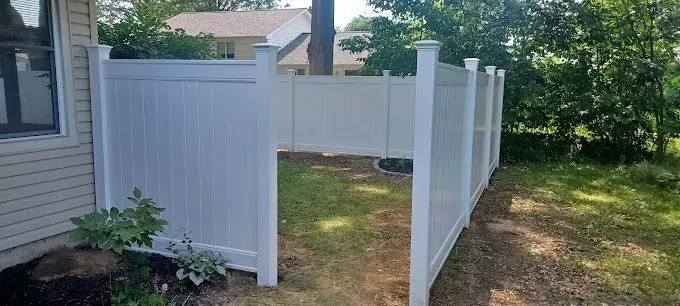 White vinyl fence surrounding a small, grassy backyard area.