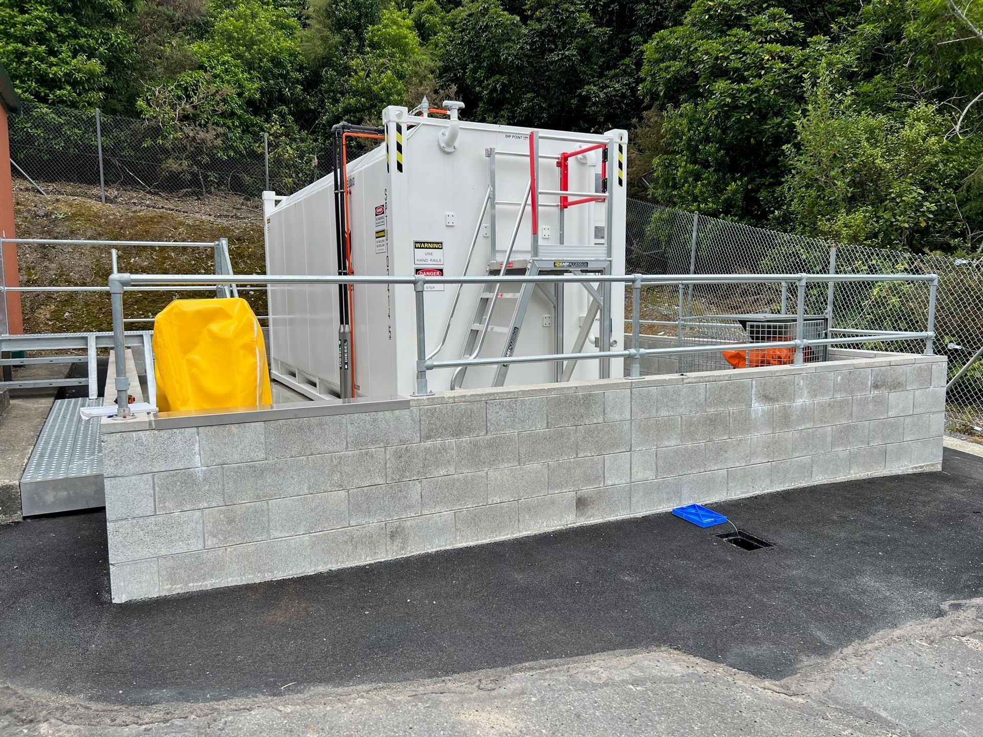 A large white tank is sitting on top of a concrete wall.