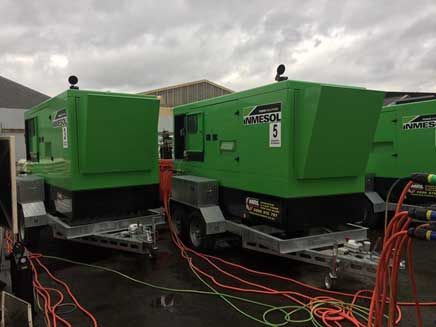 Two green generators are parked next to each other on trailers.