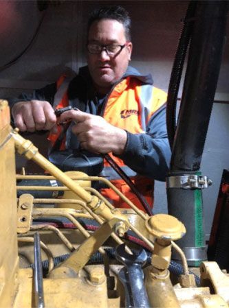 A man in an orange vest is working on a machine