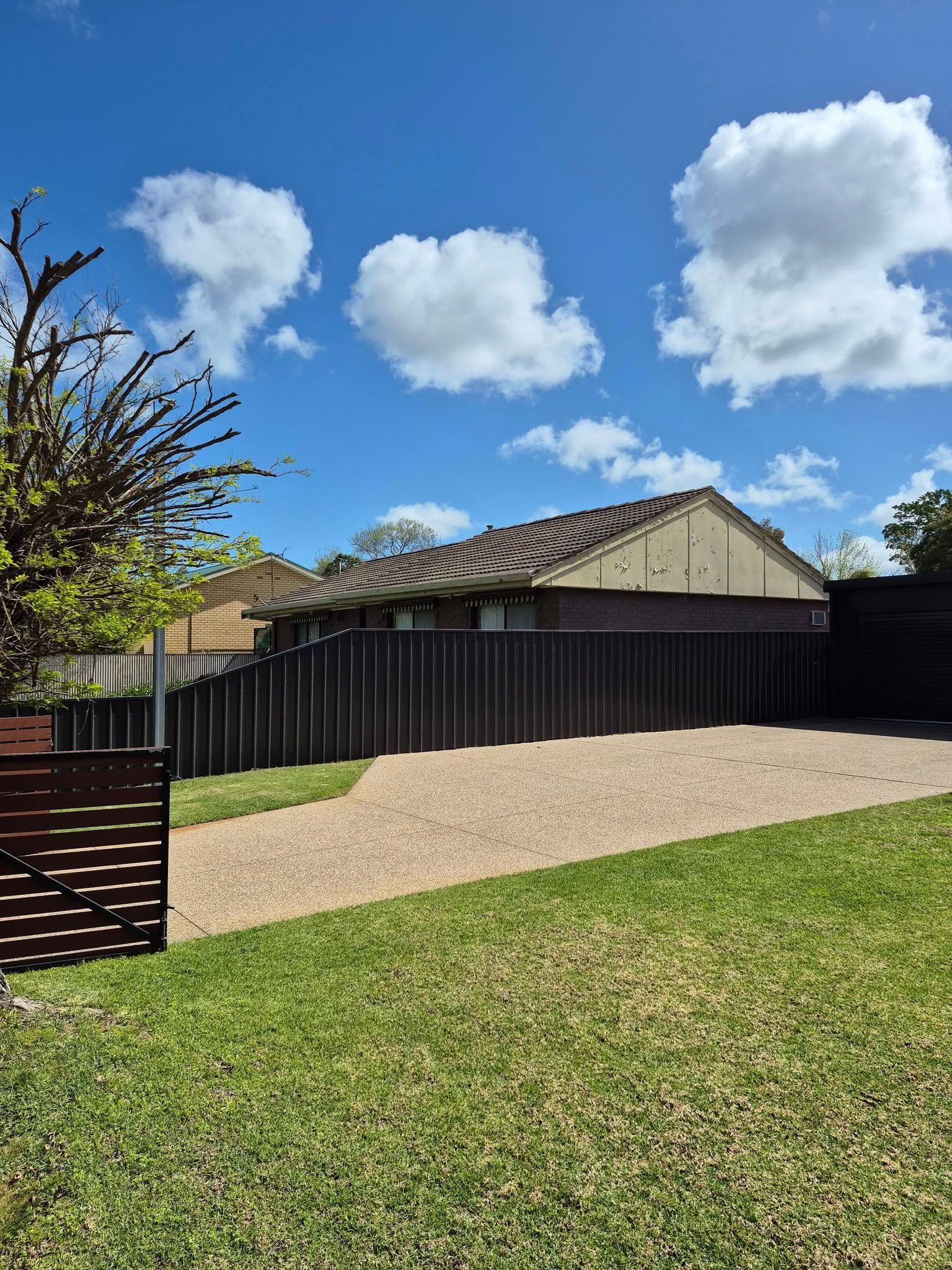 House With Brown Roof Behind a Wooden Fence — Precision Fencing & Landscaping in Thurgoona, NSW