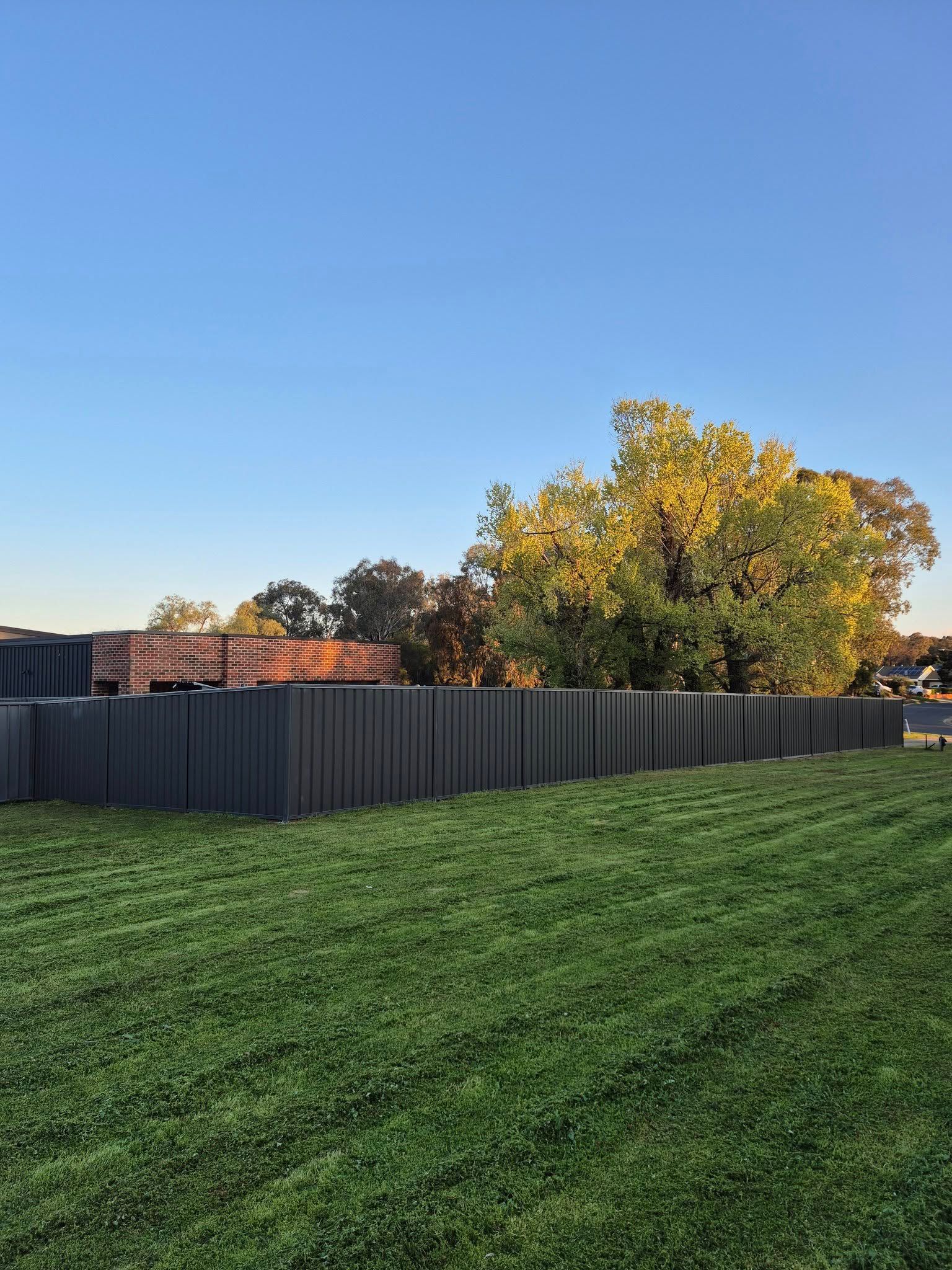 Green Lawn With a Tall, Linear, Gray Sculpture in Front of Trees — Precision Fencing & Landscaping in Thurgoona, NSW