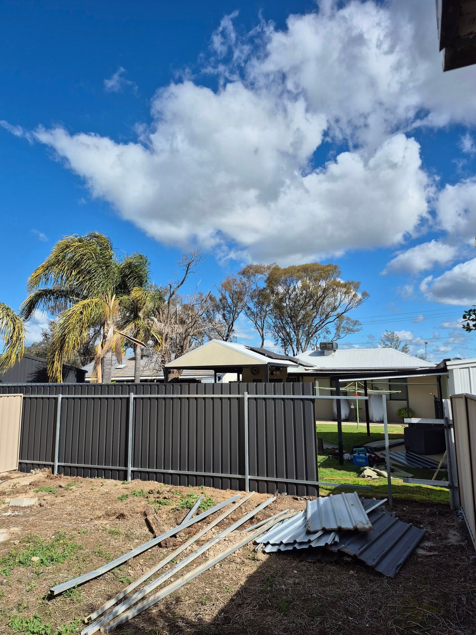 Backyard With a Dark Fence, Construction Materials — Precision Fencing & Landscaping in Thurgoona, NSW