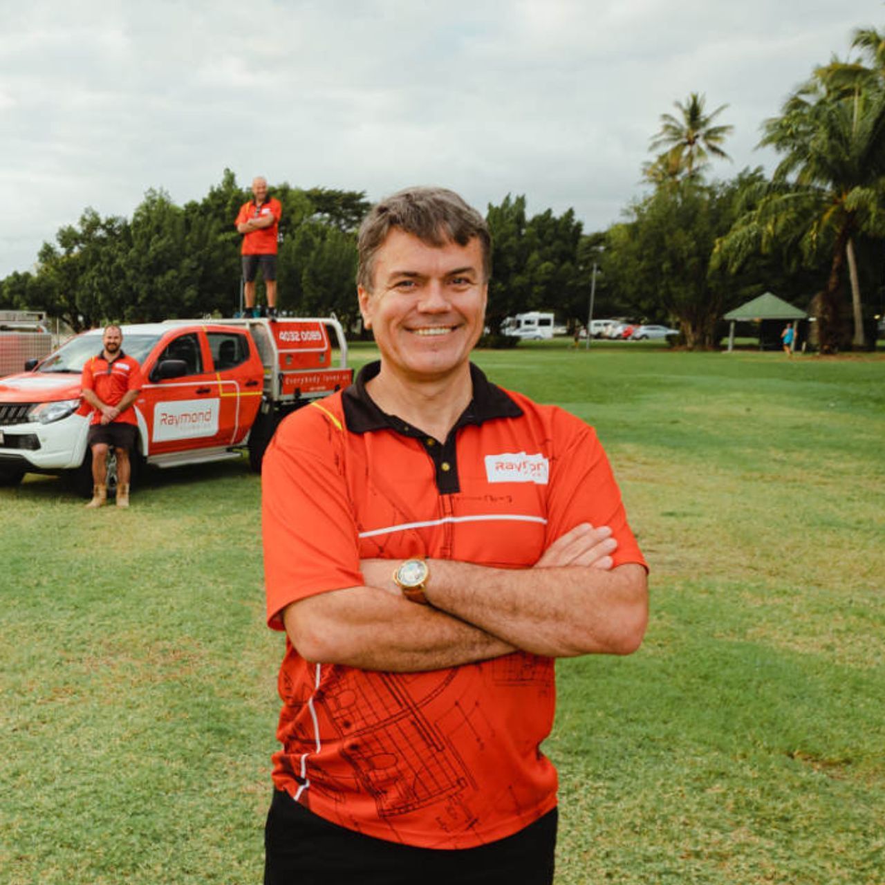 Mark Raymond from Raymond Plumbing - a man in an orange shirt is standing in a field with his arms crossed