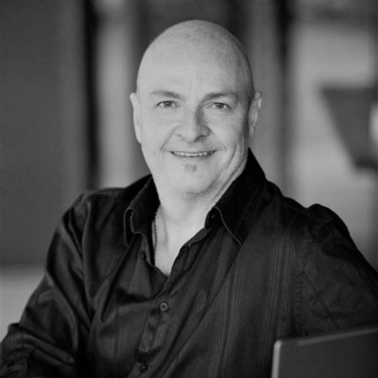 Mats Eriksson from Cairns HR Services - a bald man in a black shirt is smiling in a black and white photo .