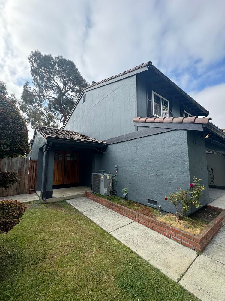 Living room with a sofa, TV, and a view of the ocean and mountains.