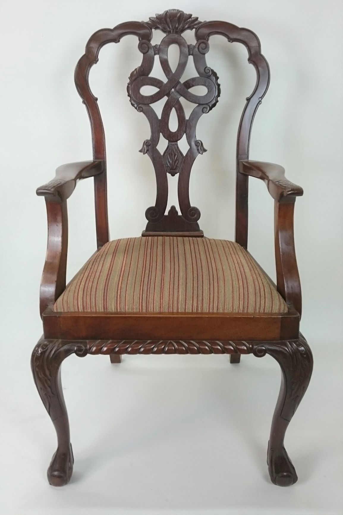 A wooden chair with a floral design on the back is sitting on a white surface.