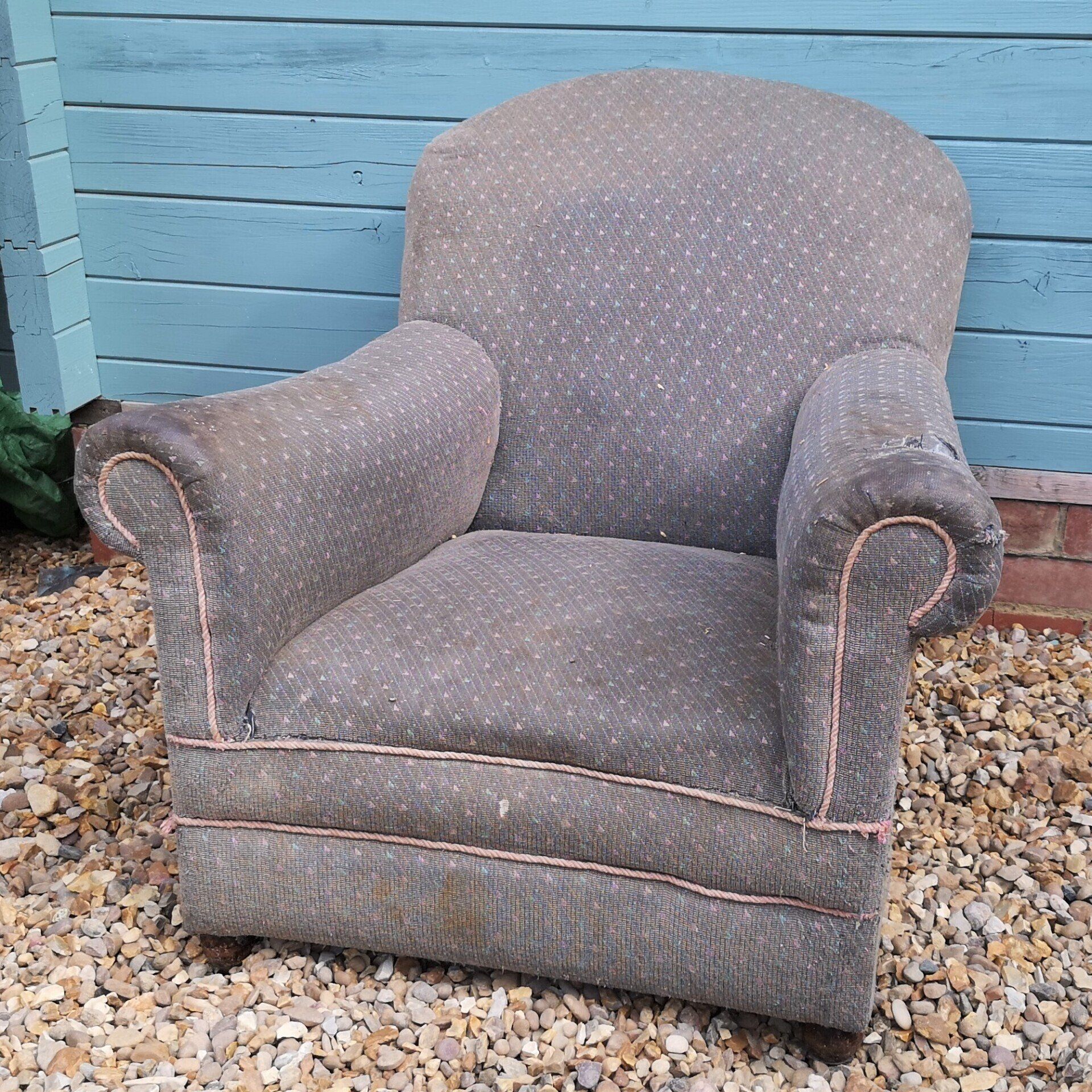 A chair is sitting on a pile of gravel in front of a blue wall
